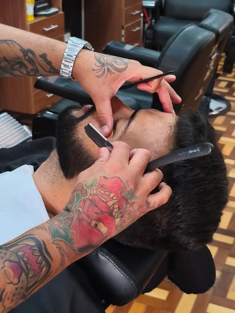 Barbeiro desenhando o contorno com navalha