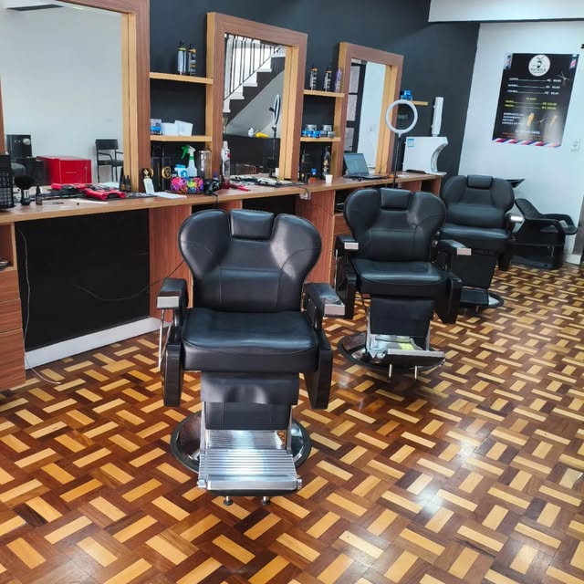 Interior da barbearia com cadeira clássica e piso de taco